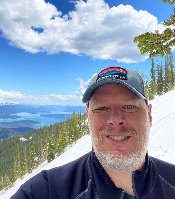Barry Campbell outside with beautiful mountains and lakes in the background.